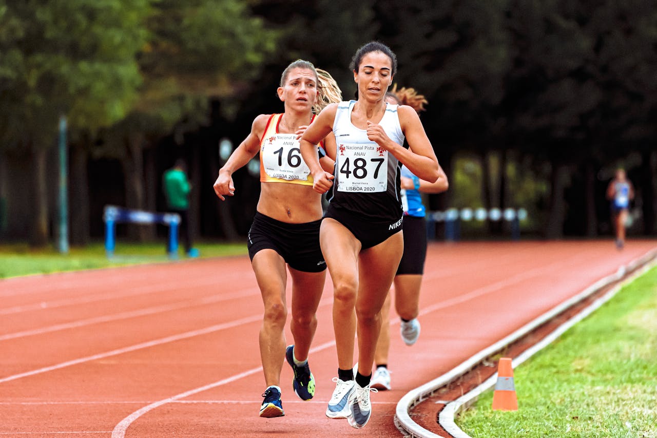 Fast athletes running on race track in stadium